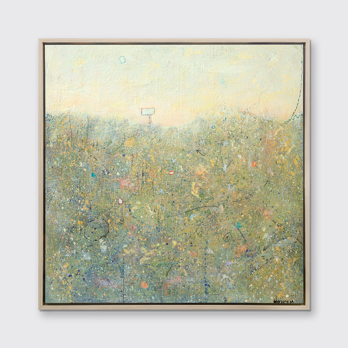 A light yellow and green abstract landscape print in a white oak wood floater frame hangs on a white wall.