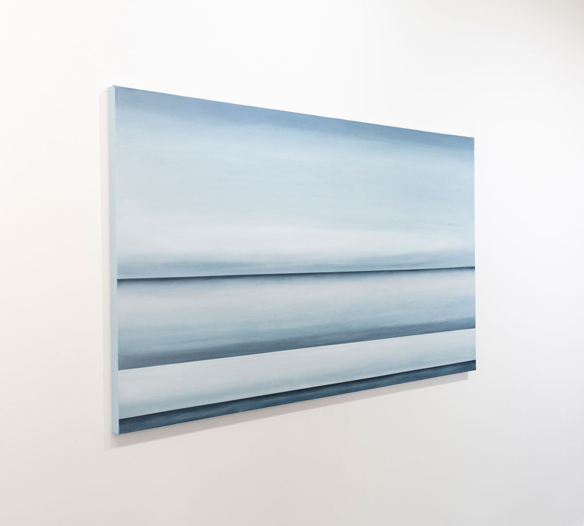 A blue oil painting with multiple navy lines dividing the canvas that suggest horizon lines is seen at an angle on a gallery wall. Wired and ready to hang.