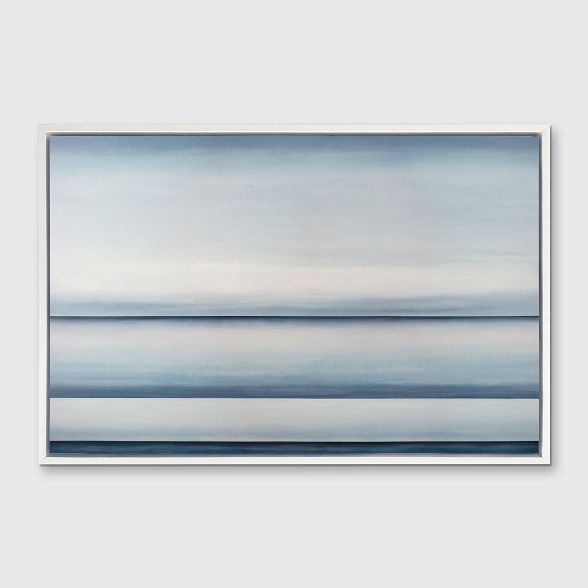 A tonal blue abstract landscape print in a white floater frame hangs on a white wall.