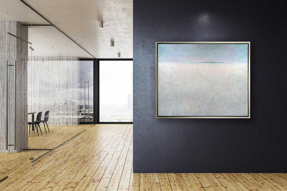 A blue and white abstract landscape print in a silver floater frame hangs on a dark grey wall across from offices with glass walls.
