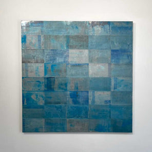 An abstract painting with a grid appearance and a blue wash by Ned Martin hangs on a white wall with a view from straight on. 