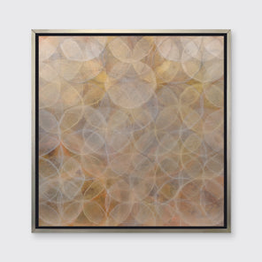 A dark yellow and white abstract overlapping circle print in a silver floater frame hangs on a white wall.