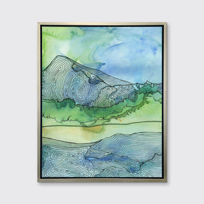 A blue and green landscape illustration print framed in a gold floater frame hangs on a light grey wall.