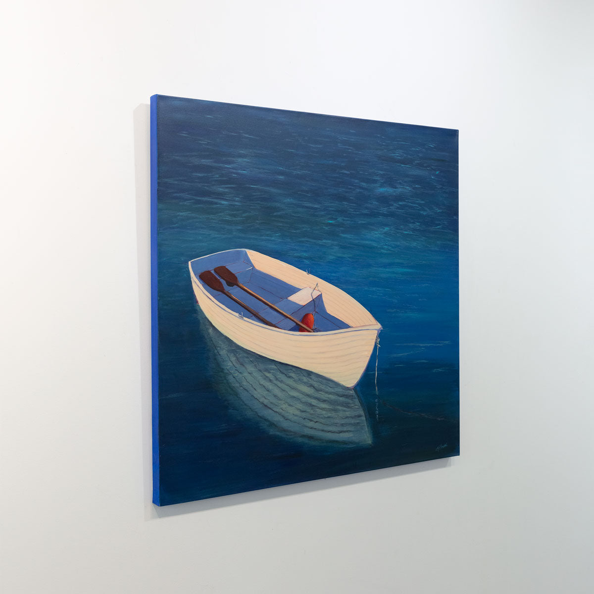 A painting of a white rowboat in deep blue water is seen at an angle on a gallery wall.