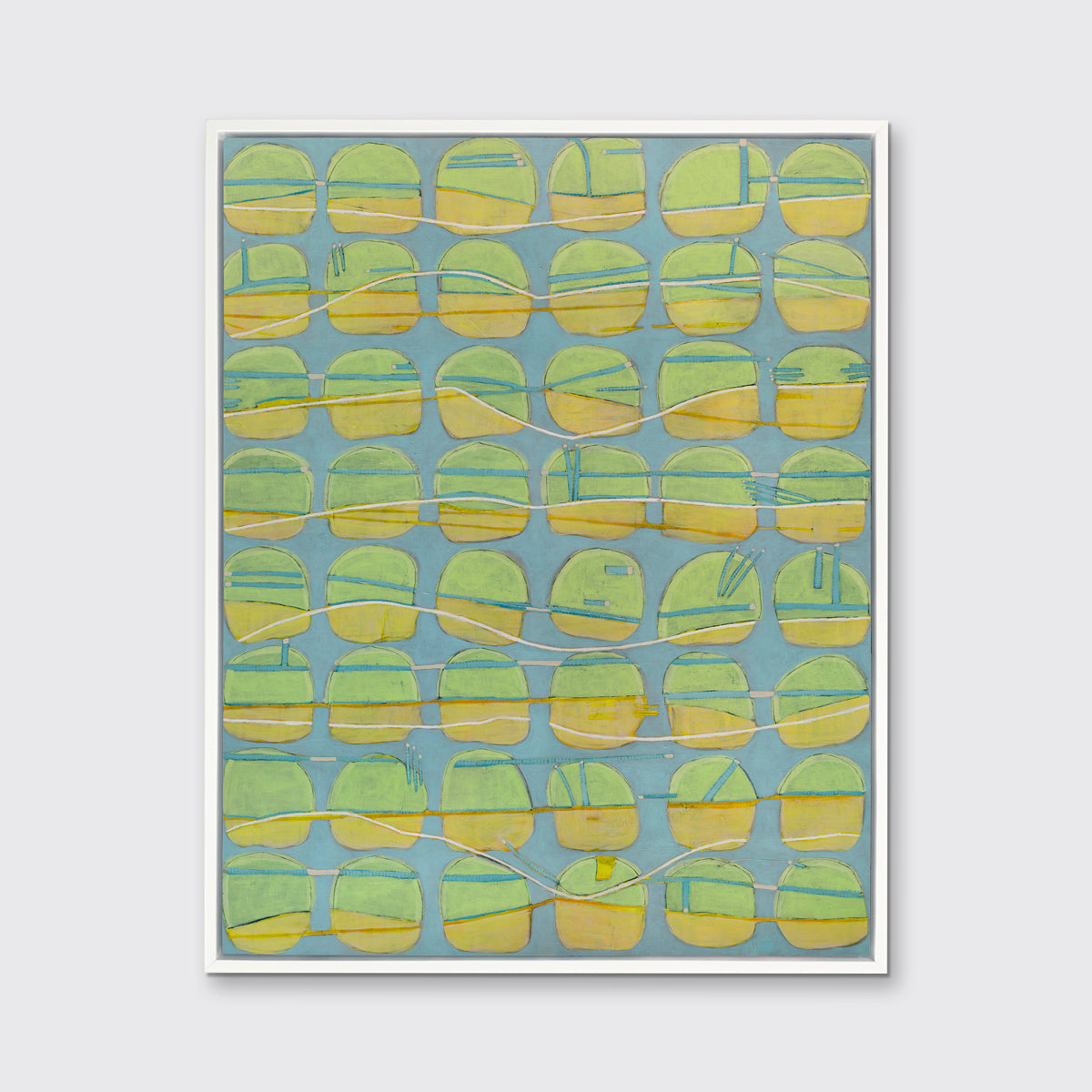 A yellow, green and light slate blue abstract circle print in a white floater frame hangs on a white wall.