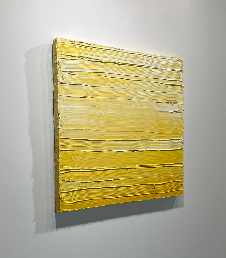 A left side-view of a textured yellow toned painting by Teodora Guererra hangs on a white wall.