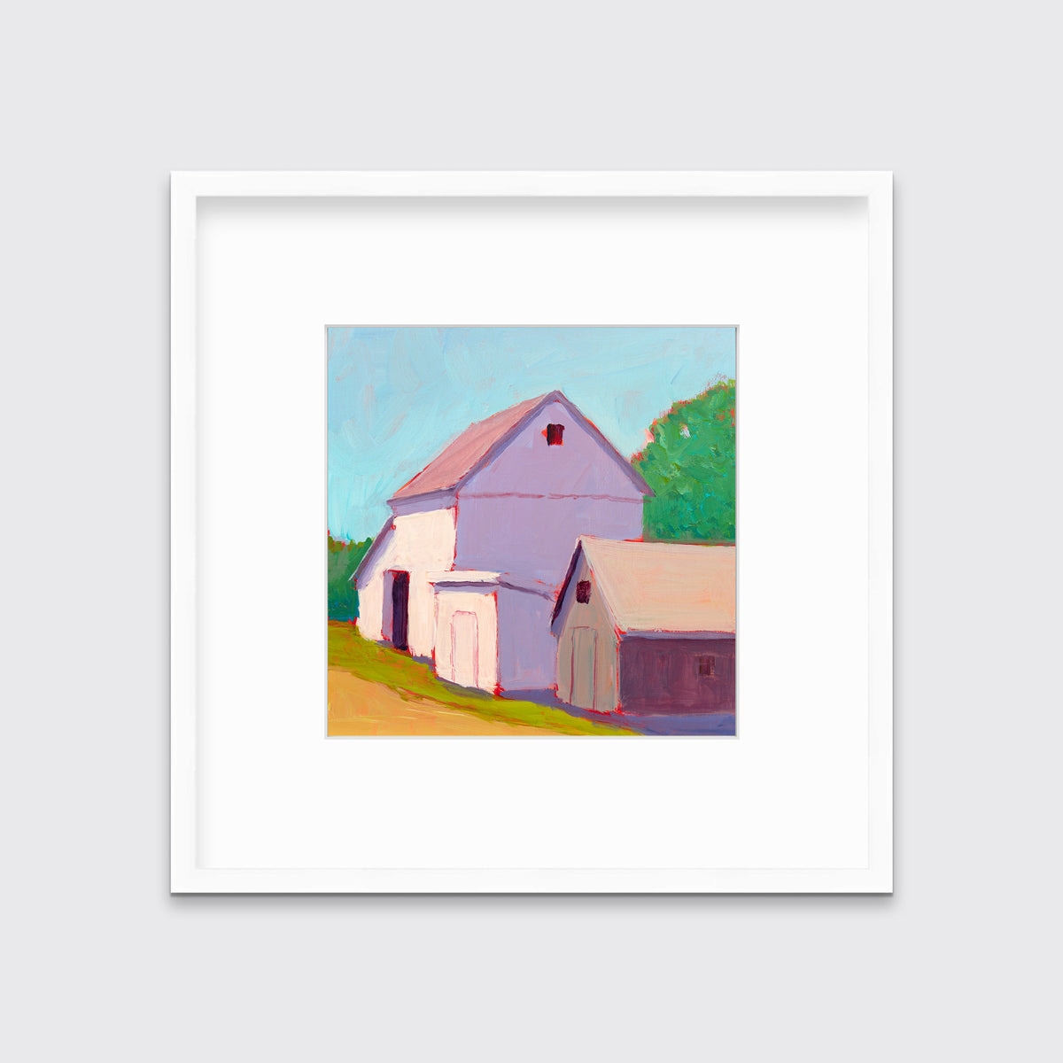 A print of a ivory barn, a smaller tan barn, a blue sky, green trees and a tan road in a white frame with a mat hangs on a white wall.
