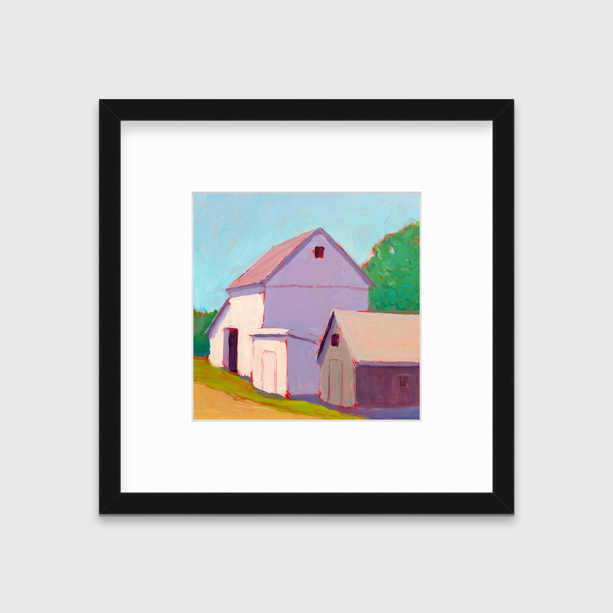 A print of a ivory barn, a smaller tan barn, a blue sky, green trees and a tan road in a black frame with a mat hangs on a white wall.