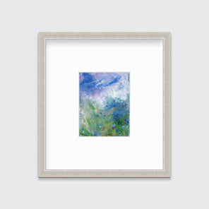 A blue, purple and green abstract print in a silver frame with a mat hangs on a white wall.