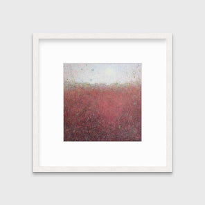 A red abstract landscape print in a whitewashed frame with a mat hangs on a white wall.