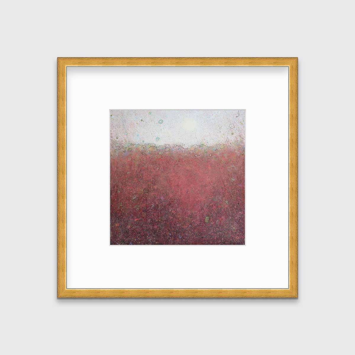 A red abstract landscape print in a gold frame with a mat hangs on a white wall.