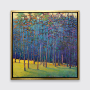 A blue, green and yellow abstract tree landscape print in a gold floater frame hangs on a white wall.