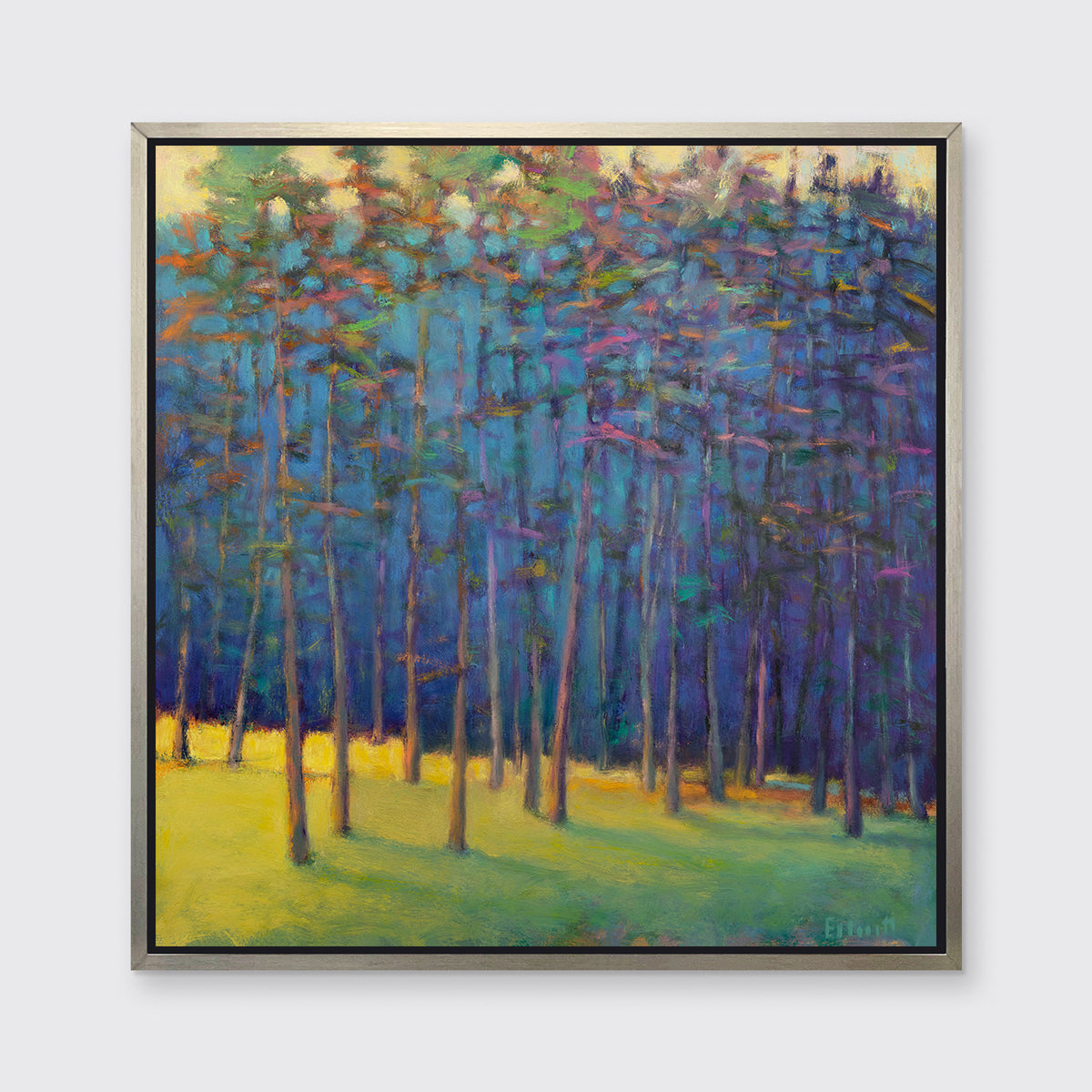 A blue, green and yellow abstract tree landscape print in a silver floater frame hangs on a white wall.