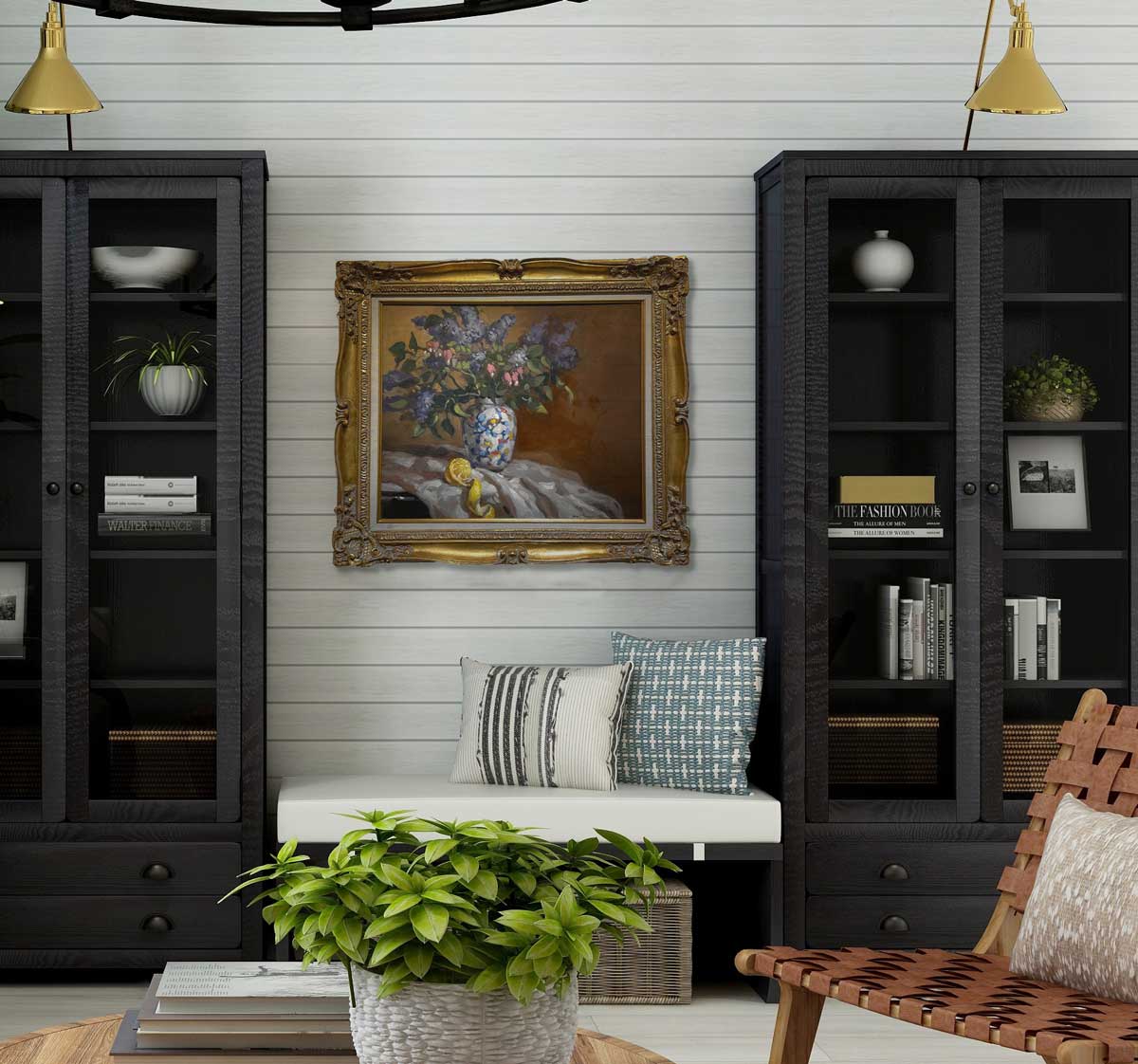 Hyperrealist painting of lilacs in a vase with peeled lemon underneath in a ornate gold frame hang on a white paneled wall between to black credenzas with a sitting area underneath the painting. The sitting area holds a white cushion and two patterned decorative pillows. 
