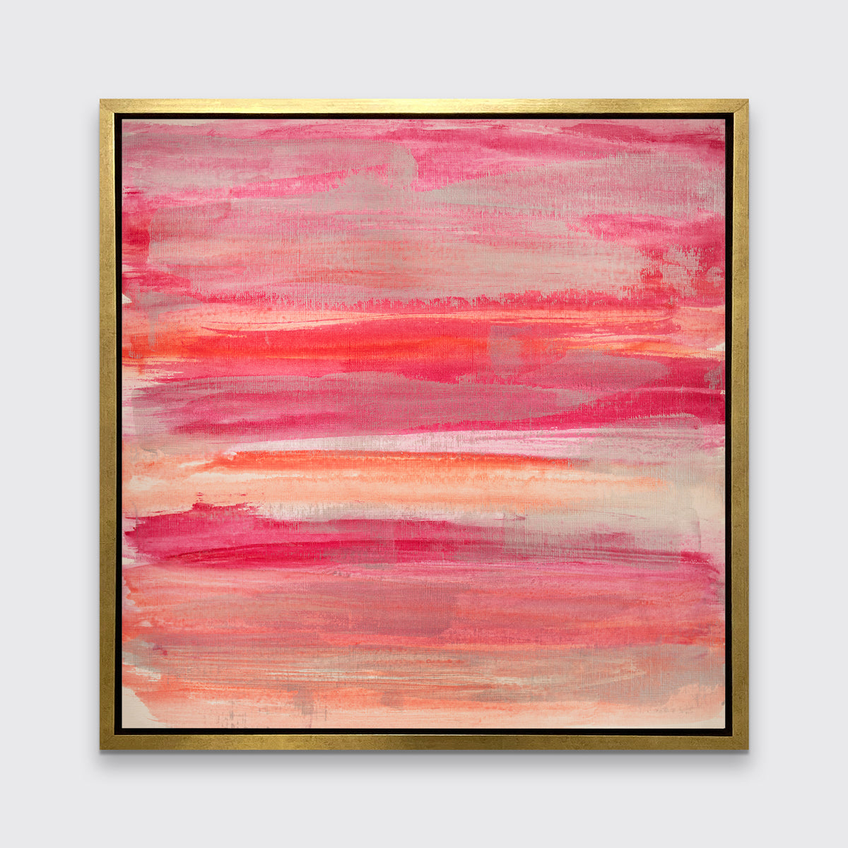 A pink, silver and orange abstract print in a gold floater frame hangs on a white wall.
