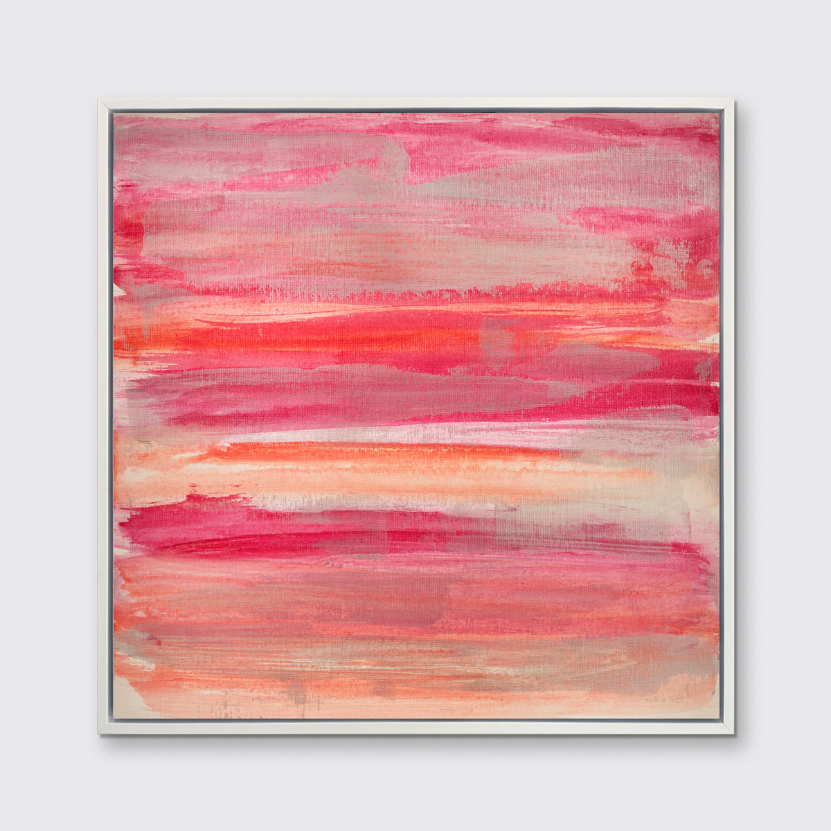 A pink, silver and orange abstract print in a white floater frame hangs on a white wall.