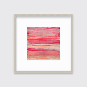 A pink, silver and orange abstract print in a silver frame with a mat hangs on a white wall.