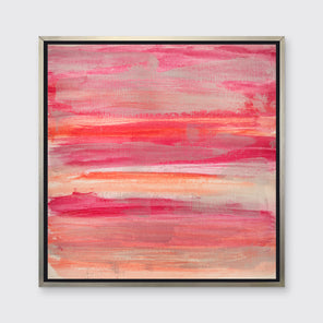 A pink, silver and orange abstract print in a silver floater frame hangs on a white wall.