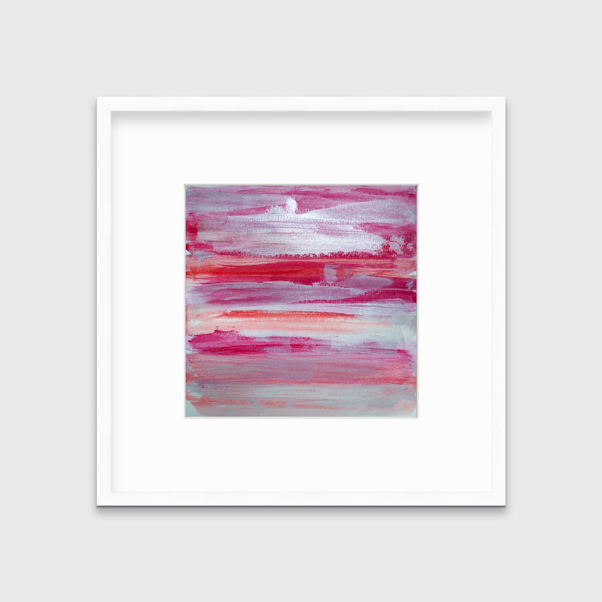 A pink, white, silver and red abstract print in a white frame with a mat hangs on a white wall.