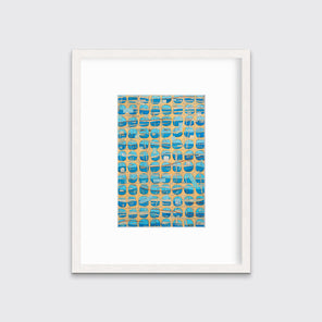 An orange, blue and light blue abstract print in a whitewashed wood frame with a mat hangs on a white wall.
