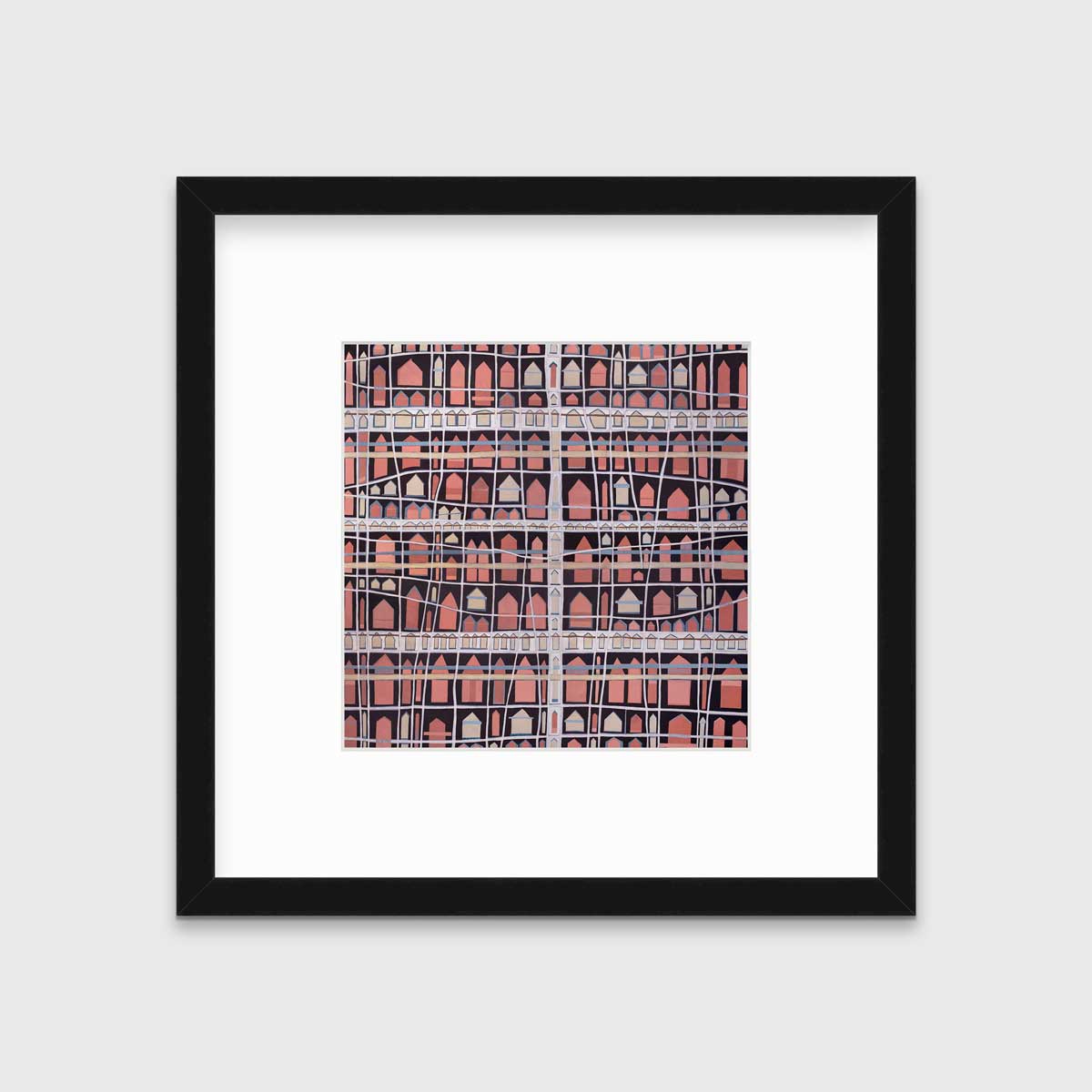A pink, white and black abstract house print in a black frame with a mat hangs on a white wall.
