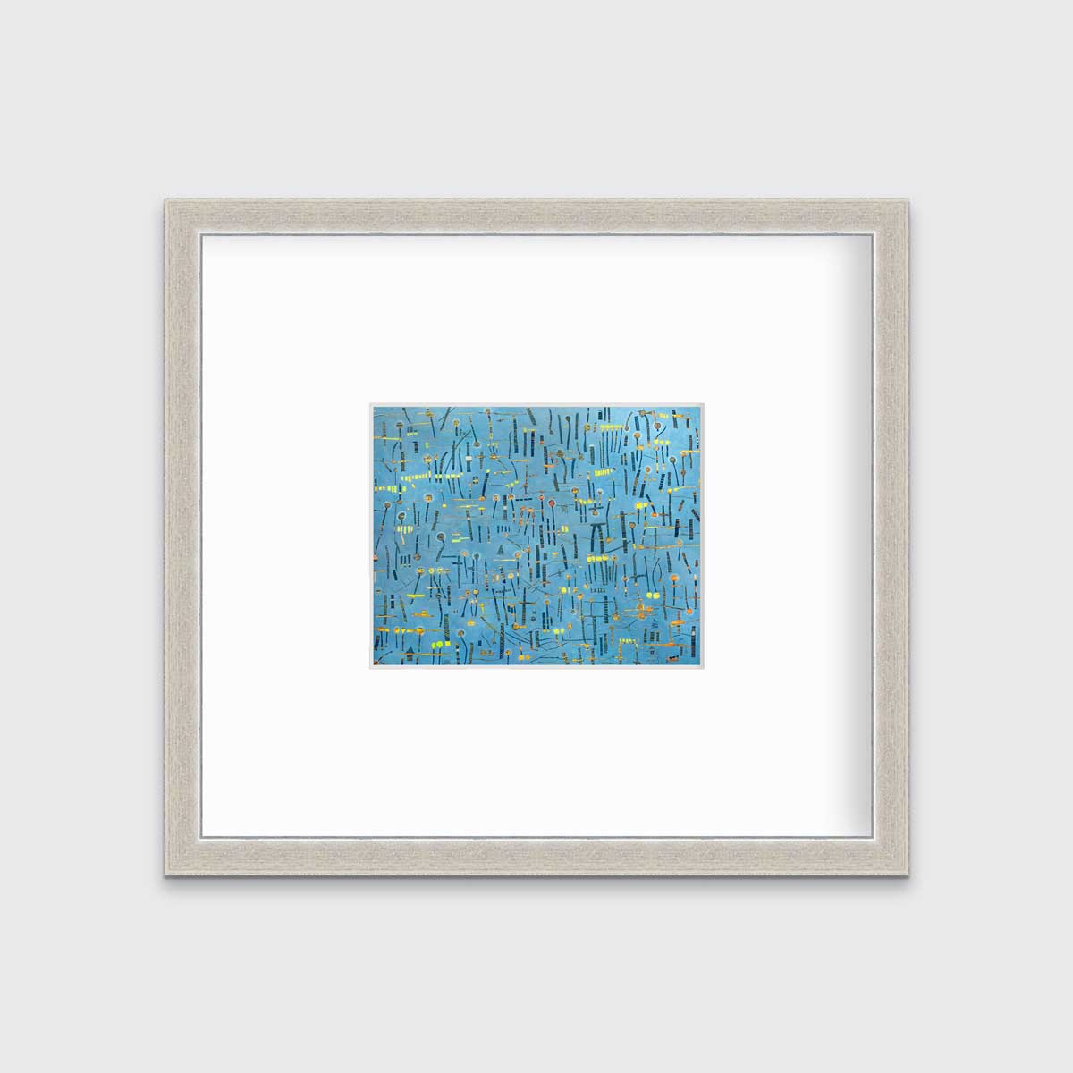 A blue, yellow and orange abstract print in a silver frame with a mat hangs on a white wall.