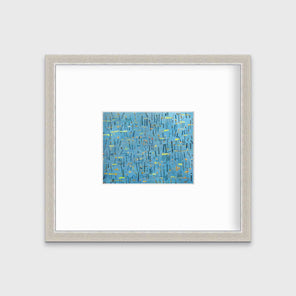 A blue, yellow and orange abstract print in a silver frame with a mat hangs on a white wall.