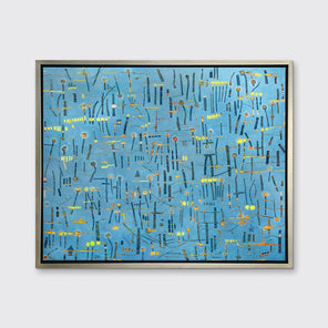 A blue, yellow and orange abstract print in a silver floater frame hangs on a white wall.