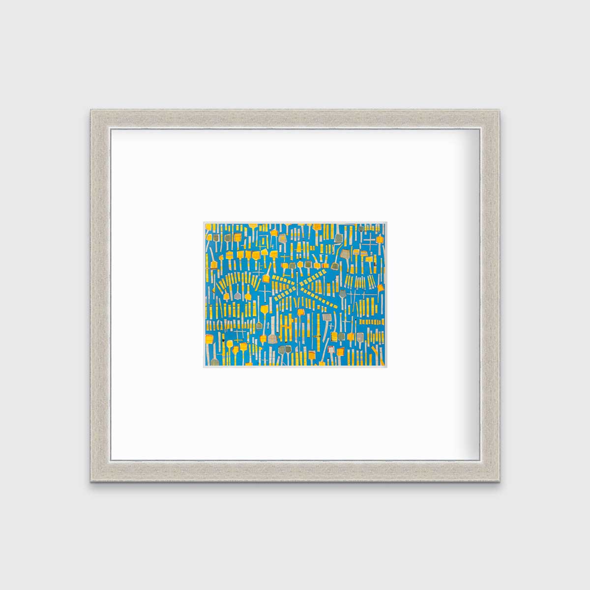 A blue and yellow abstract print in a silver frame with a mat hangs on a white wall.