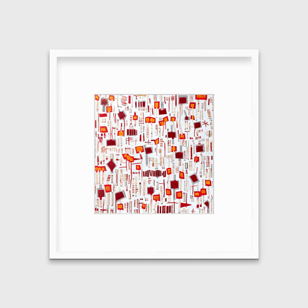 A red, white and orange abstract print in a white frame with a mat hangs on a white wall.