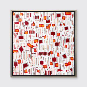 A red, white and orange abstract print in a silver floater frame hangs on a white wall.