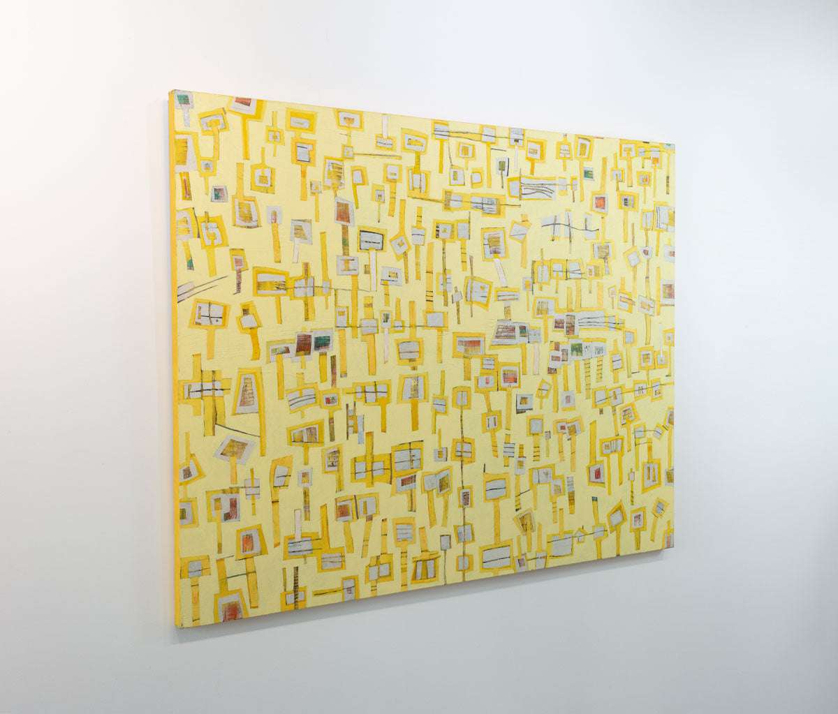 An abstract painting of yellow "lollipops" on a yellow background is seen at an angle on a gallery wall.