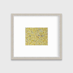 A yellow and grey abstract print in a silver frame with a mat hangs on a white wall.