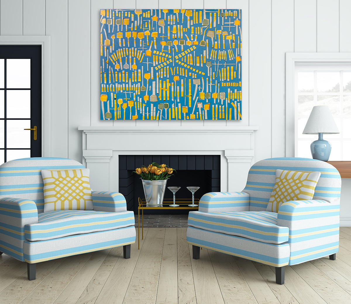 An abstract panting of yellow sticks and "lollipops" on a blue background is hung above a fireplace in a living room. 