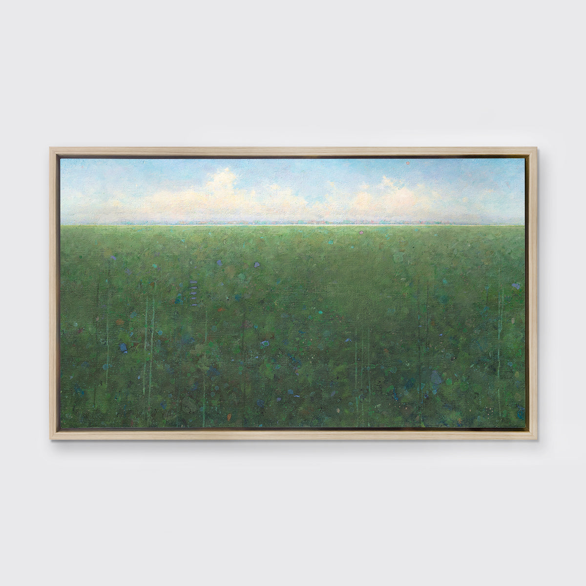 A green, light blue and white abstract landscape print in a white oak wood floater frame hangs on a white wall.