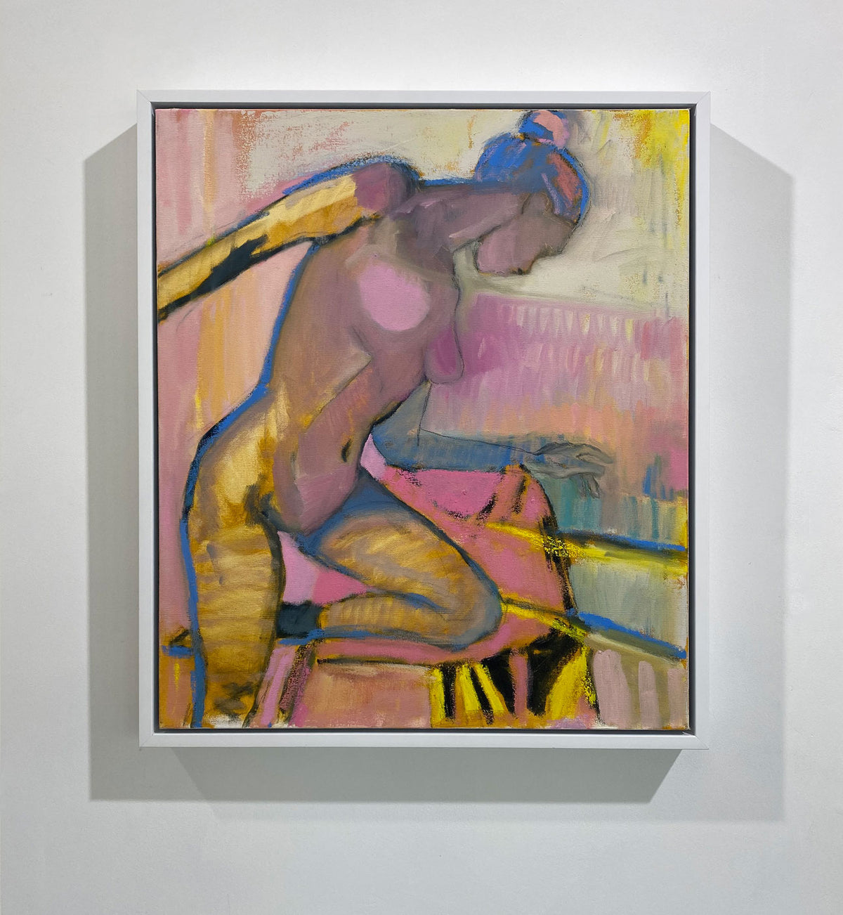 A warm-toned abstract figurative painting hangs in a white frame on a clean, white wall. 