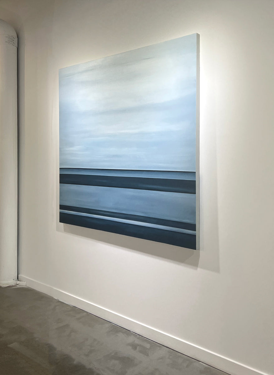 A right side-angle view of a tonal blue linear abstract painting by Tony Iadicicco hangs on a white wall.