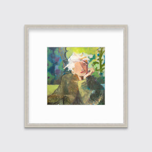 A green, beige and white abstract figural print in a silver frame with a mat hangs on a white wall.
