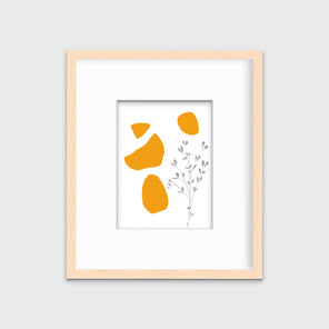 A minimal abstract print of a lavender wildflower with orange geometric shapes by Hazal Ozturk in a natural wood frame with a mat hangs on a white wall.
