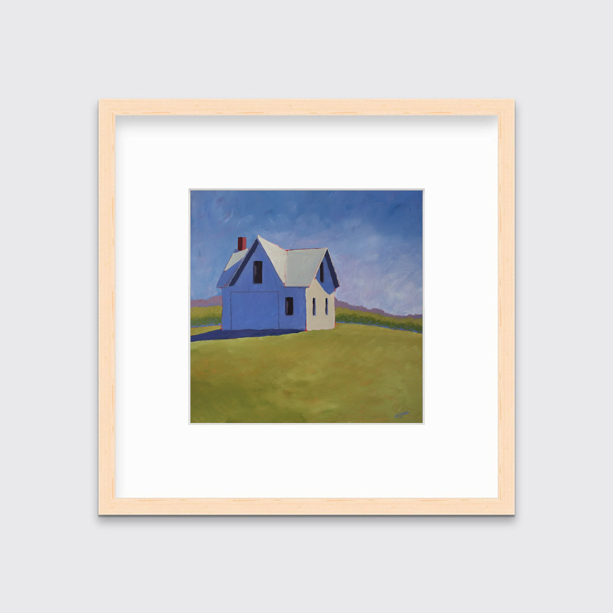 A blue and green contemporary barn print in a natural wood frame with a mat hangs on a white wall.