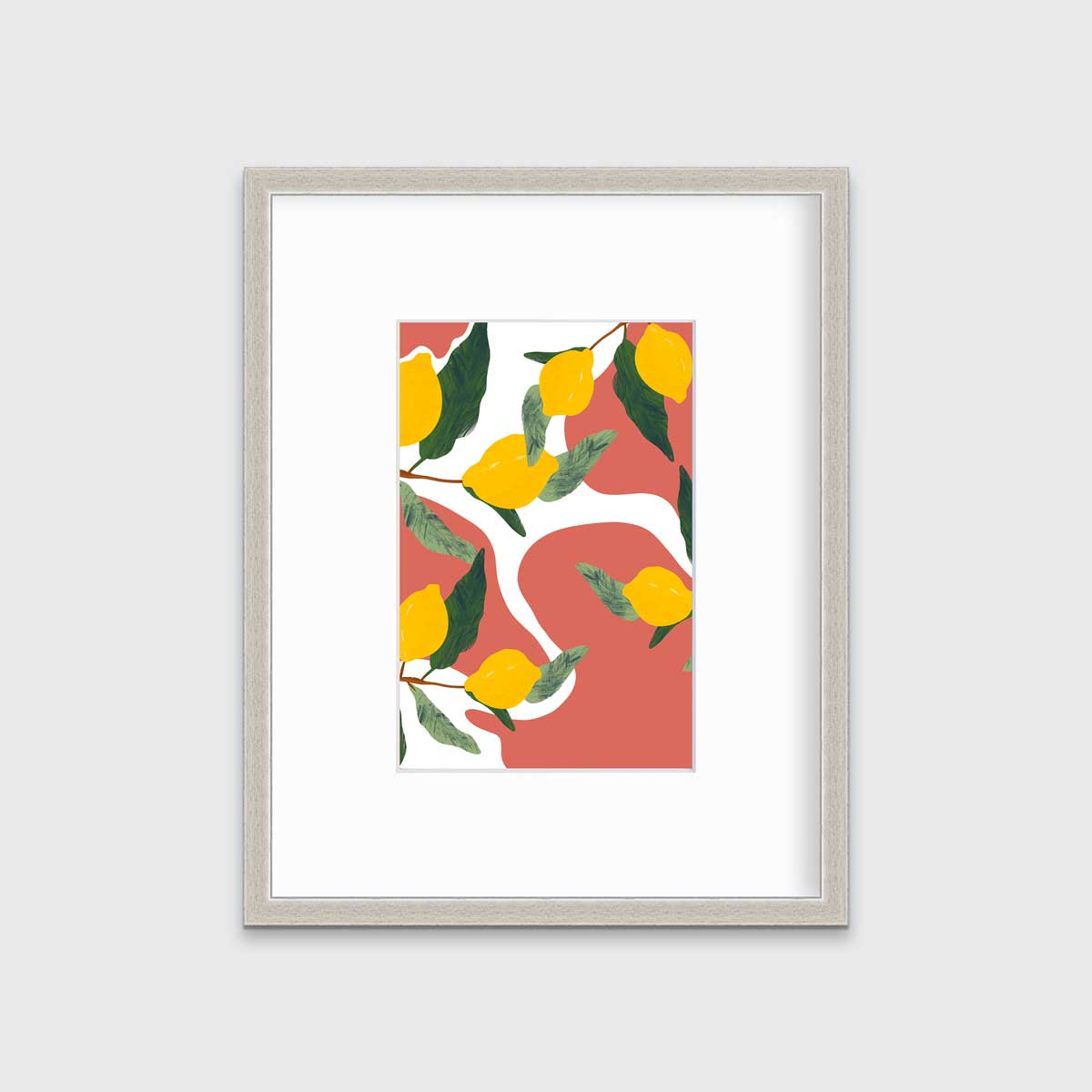 A print of lemons on branches with a terracotta and white organically shaped background in a silver frame with a mat hangs on a white wall.