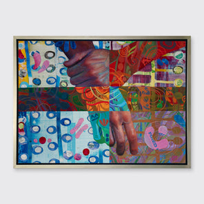 A multicolored abstract print of two hands in a silver floater frame hangs on a white wall.