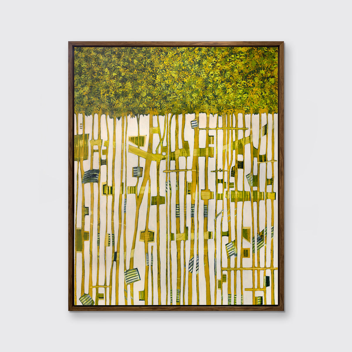 A green, yellow and white abstract print in an oak wood floater frame hangs on a white wall.
