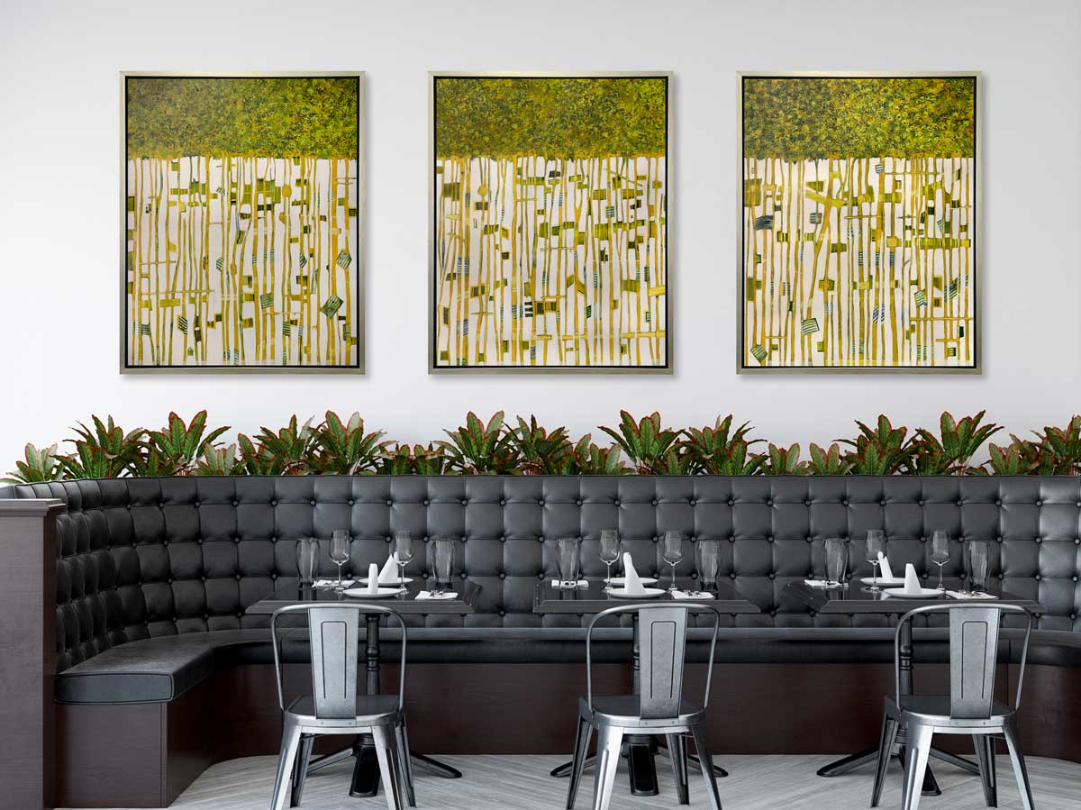 Three green, yellow and white abstract prints in silver floater frames hang on a white wall above a long black tufted booth, black tables and black chairs.