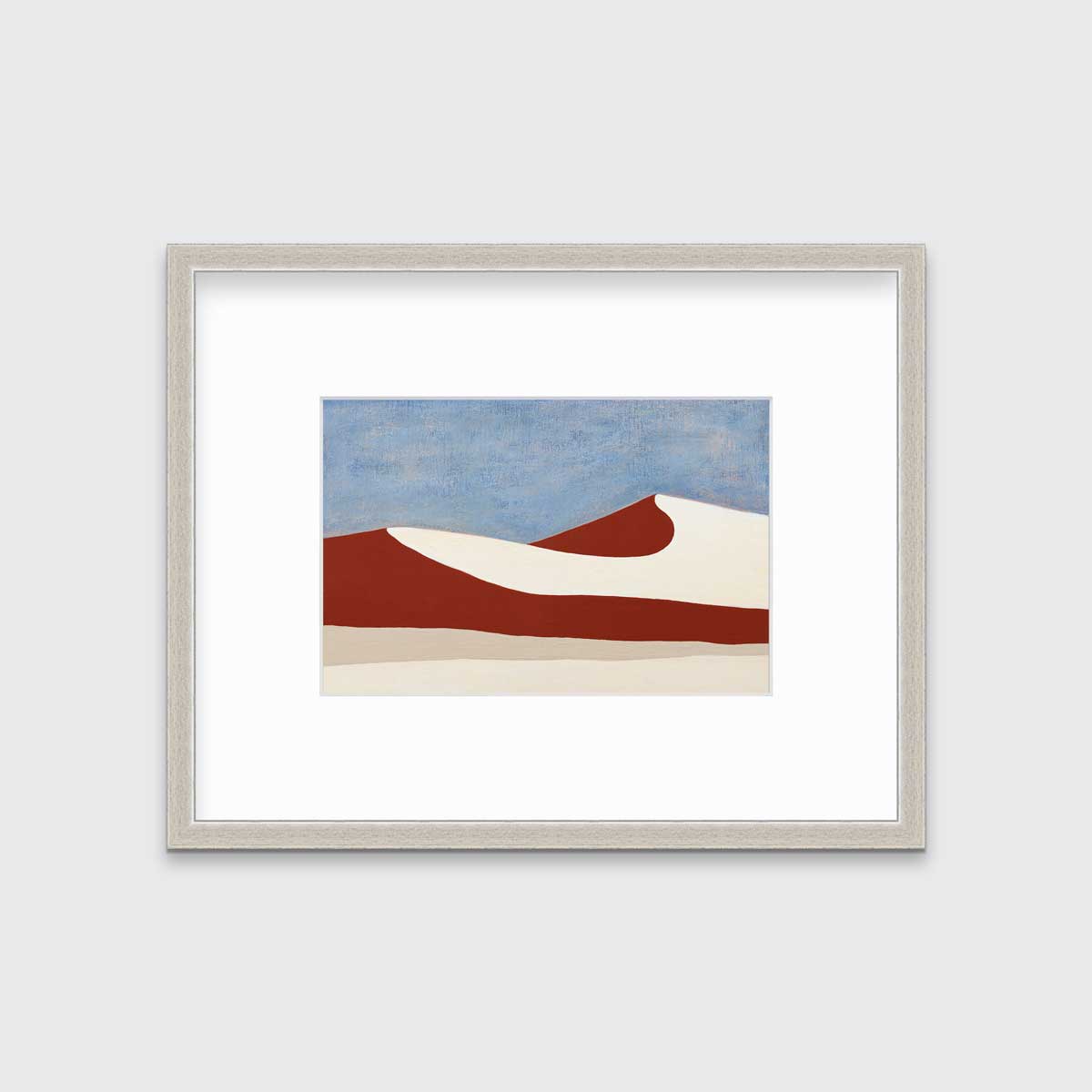 A blue, red and beige abstract landscape print in a silver frame with a mat hangs on a white wall.