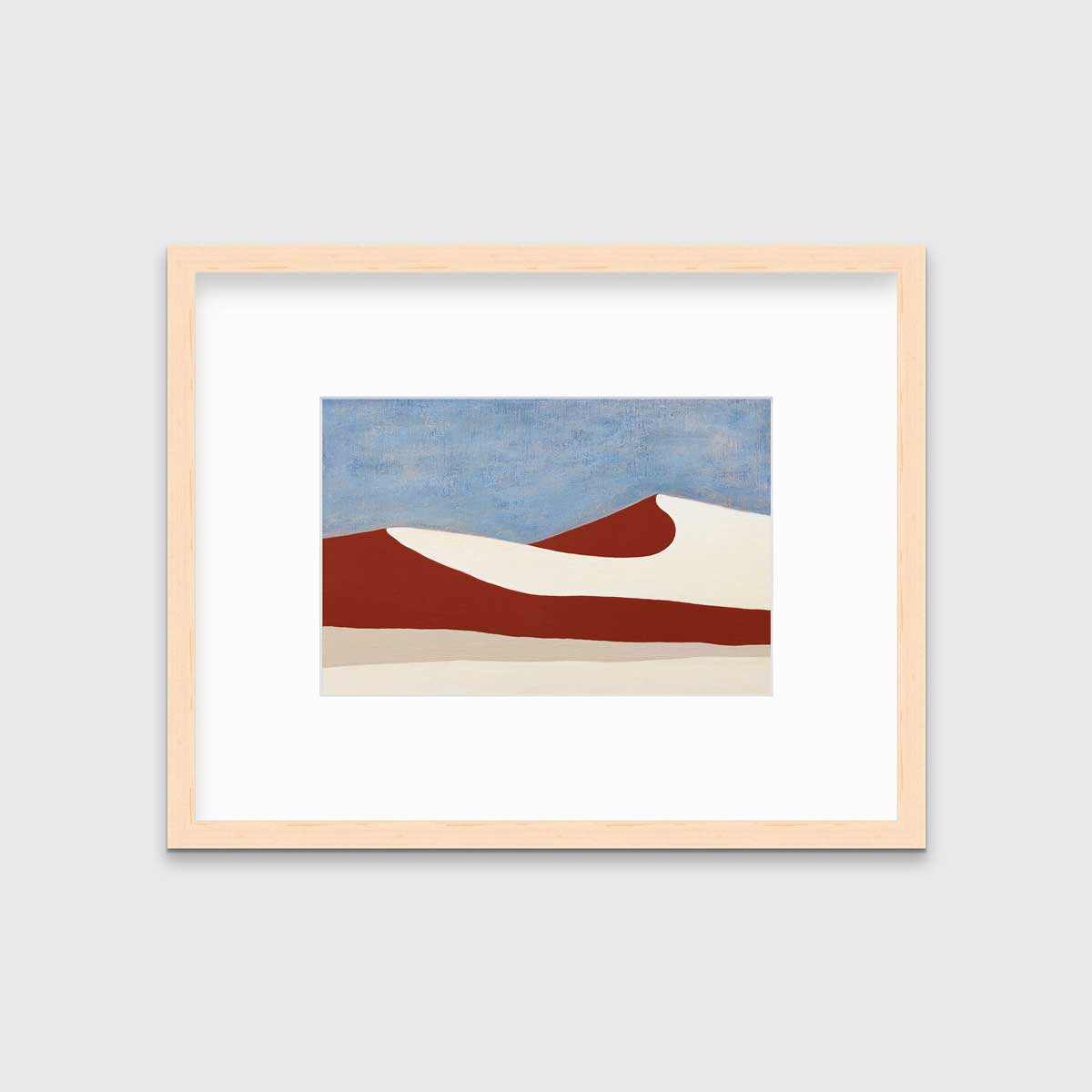 A blue, red and beige abstract landscape print in a natural wood frame with a mat hangs on a white wall.