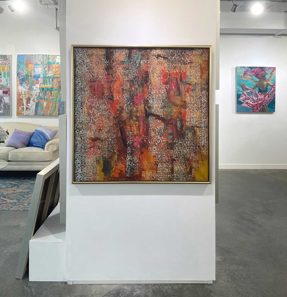 A multicolored abstract painting by Stanley Bate in a warm gold frame hangs on a white wall.