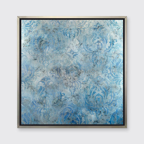 A dark blue, light blue and silver abstract print in a silver floater frame hangs on a white wall.