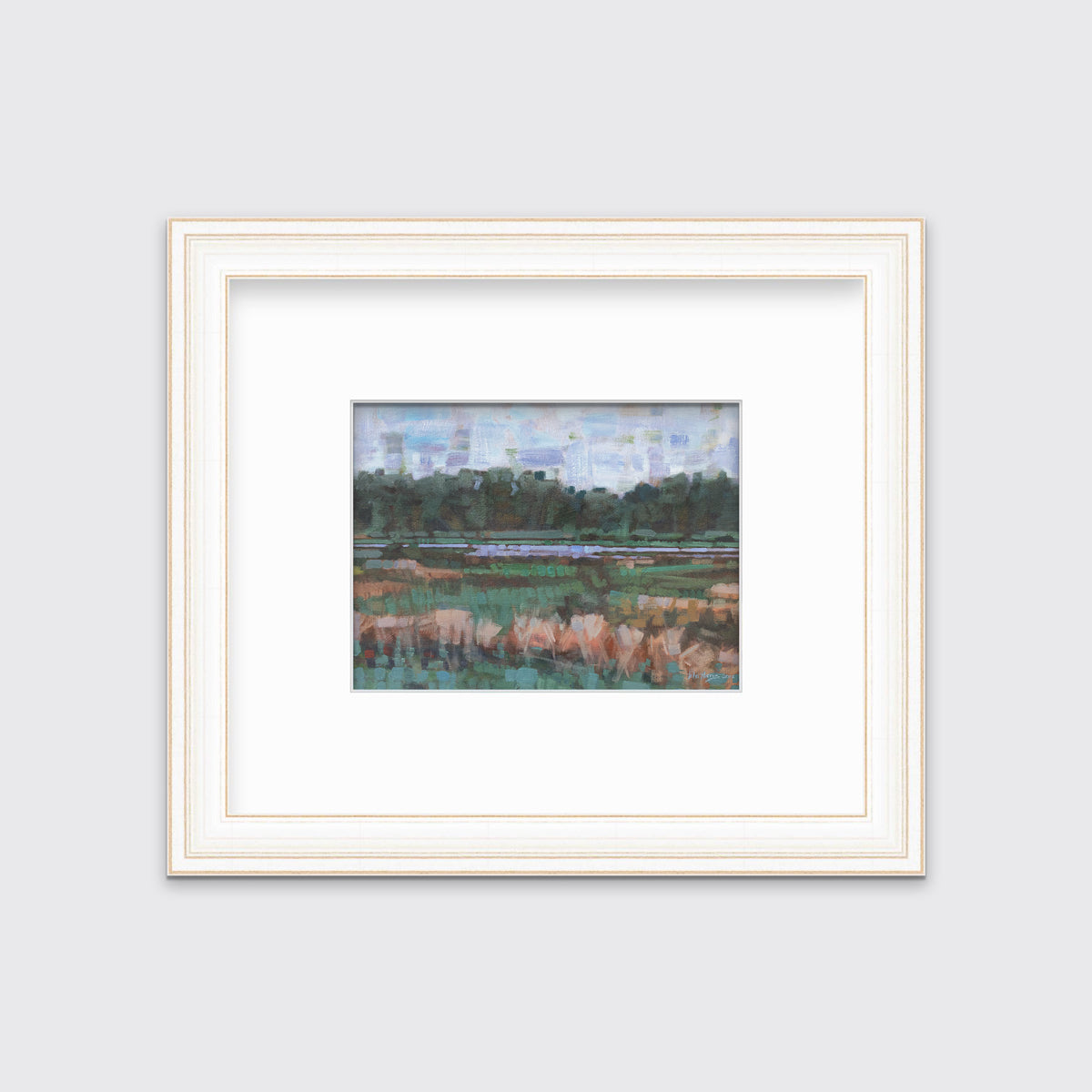 A green, orange and blue abstract landscape print in a white and gold frame with a mat hangs on a white wall.