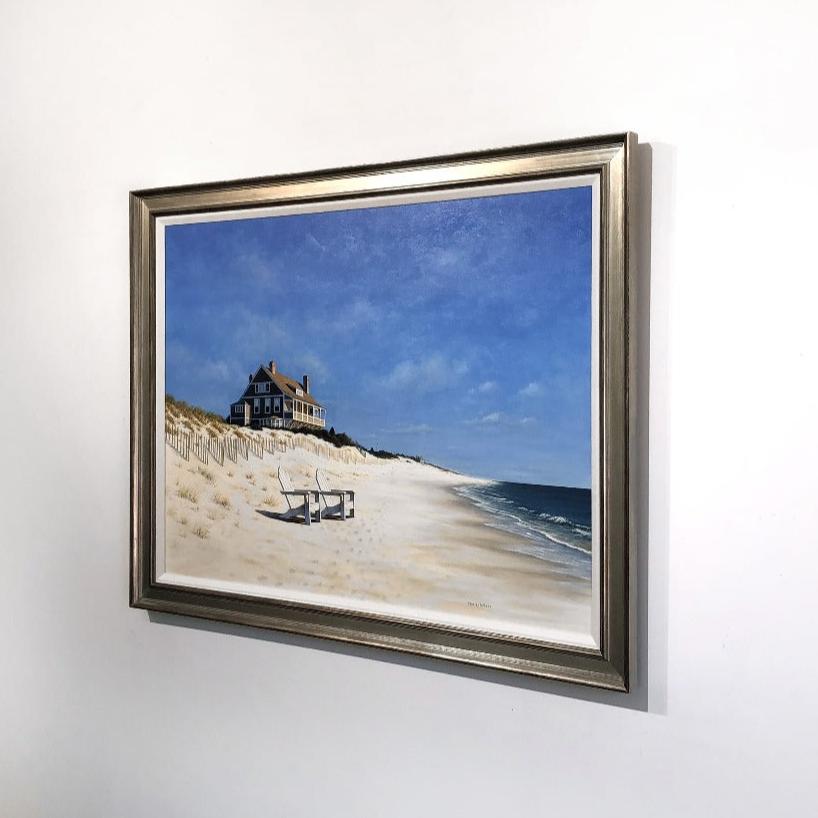 A right side-angle view of a painting of a realist coastal print framed on a white wall.